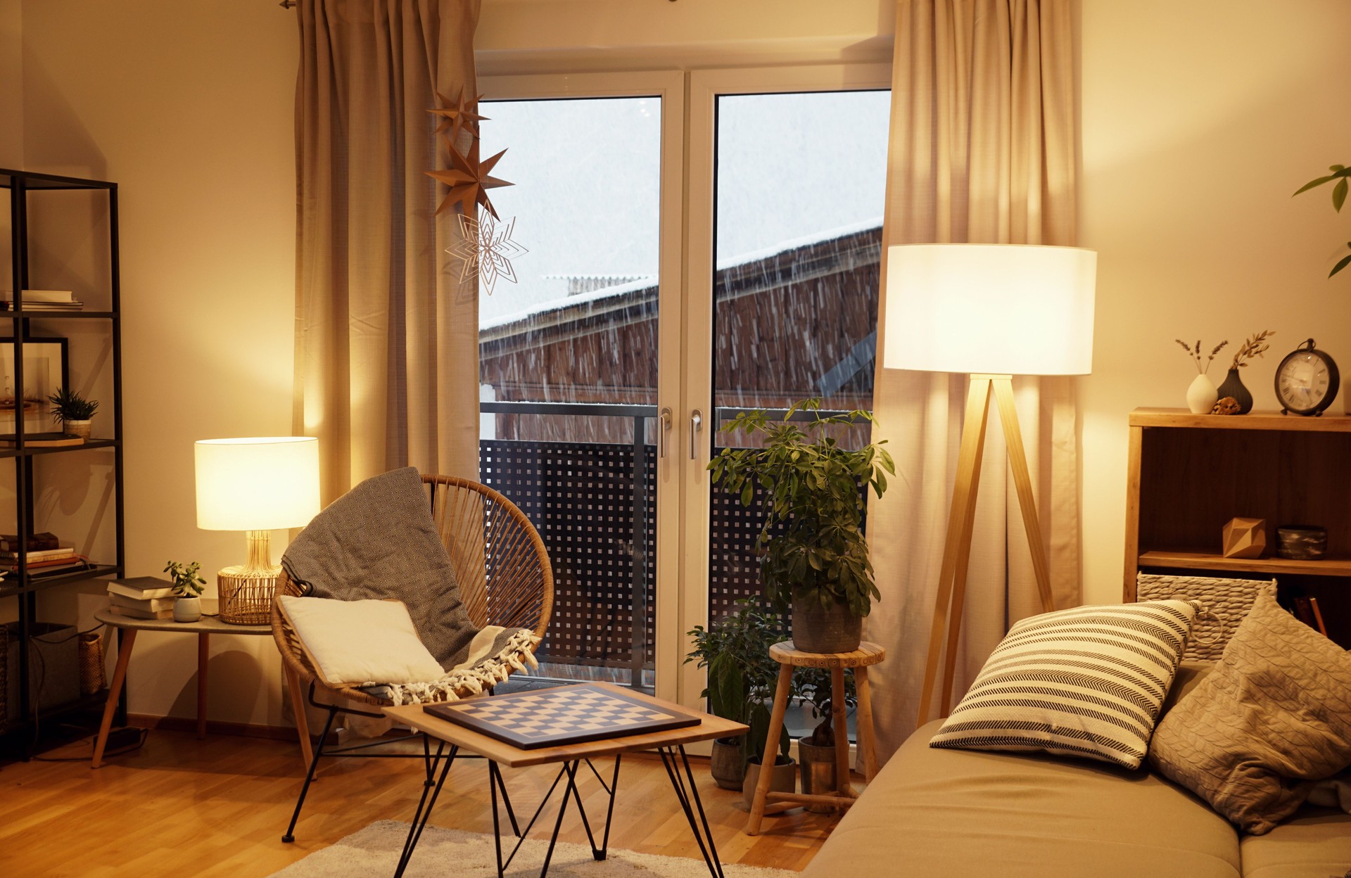 View of a warm light cozy living room in winter with a snowstorm outside